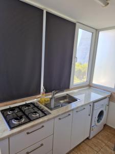 a kitchen with a stove and a sink and two windows at Studio modern. in Bucharest +6 photos