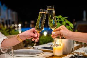Due persone che tengono bicchieri da vino a un tavolo di Skiathos Avaton Garden, Philian Hotels and Resorts a Città di Skiathos