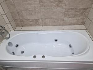 a white bath tub in a bathroom with tiles at Apartament Rezidențial in Suceava