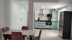 cocina con mesa, sillas y nevera en Apartamentos las flores en Murcia