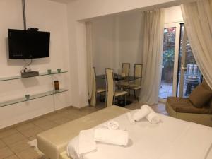 a living room with a bed and a tv and a table at CALM SUITE in Sitia