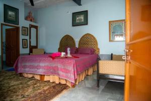 a bedroom with a table and two chairs with a pink bed at Little prince guest house & homestay in Bikaner