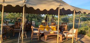 ein großes Zelt mit einem Tisch, Stühlen und einem Tisch in der Unterkunft Makubi Safari Camp by Isyankisu in Kwa Mhinda