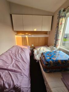 a small bedroom with two beds and a window at Caravan 4 - Cambrian Coast Caravan Park in Borth