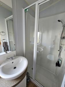 a white bathroom with a shower and a sink at Caravan 4 - Cambrian Coast Caravan Park in Borth
