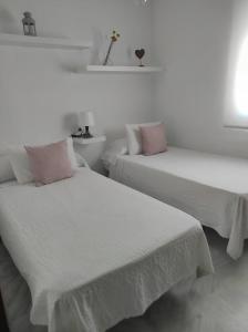 two beds in a room with white walls and pink pillows at Idalia 19 Atico in Sanlúcar de Barrameda +7 photos