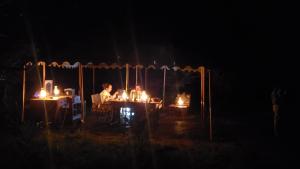 Kwa Mhinda的住宿－Makubi Safari Camp by Isyankisu，一群人坐在一张桌子上,在黑暗中