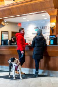 a man and a woman standing at a counter with a dog at Lake Louise Inn in Lake Louise