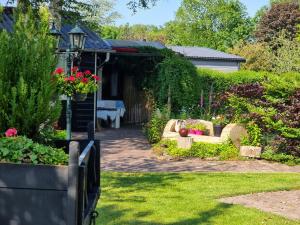 einen Garten mit einer Bank und Blumen im Hof in der Unterkunft De Veldeling in Hollandscheveld