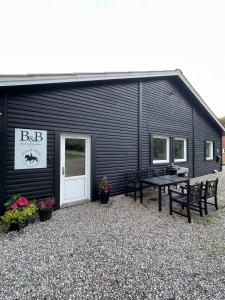 a black building with a picnic table and benches at B&B Stald Saga in Herning