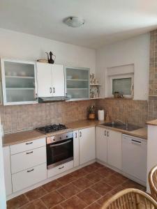 cocina con armarios blancos y fogones en Apartment Petrovic, en Pirovac