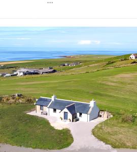 an aerial view of a white house in a field at Reka Vik in Stromness