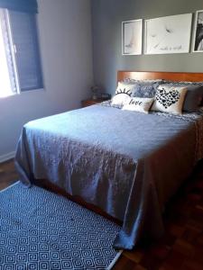um quarto com uma cama com um cobertor azul e almofadas em APARTAMENTO PRAIA GRANDE-CANTO DO FORTE- 2 QUADRAS DA PRAIA WI-FI,NETFLIX e ESTACIONAMENTO na Praia Grande