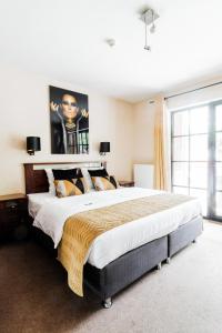 ein großes Bett in einem Schlafzimmer mit einem großen Fenster in der Unterkunft Turnhout City Hotel in Turnhout