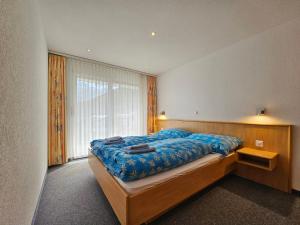 ein Schlafzimmer mit einem großen Bett mit blauer Bettwäsche und einem Fenster in der Unterkunft Nicoletta in Saas-Fee