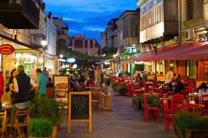 Un grupo de personas sentadas en mesas en una calle por la noche. en Old Town Italian Courtyard, en Tiflis