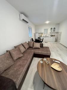 uma sala de estar com um sofá grande e uma mesa de madeira em Knežević apartman 