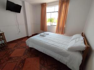 a bedroom with a white bed and a window at Soinca Backpacker Hospedaje in Paracas