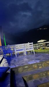 two white benches sitting on a patio at night at Villat Grand in Peje