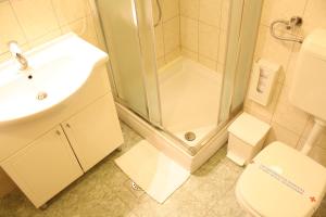a bathroom with a shower and a toilet and a sink at Hotel Mediteran in Zadar