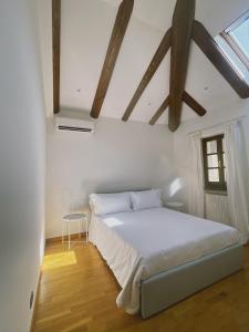 a bedroom with a white bed and wooden ceilings at Casa Lobe - Charming apartment in village centre in La Morra