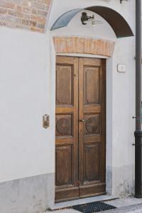 una puerta de madera en una pared blanca con un arco en Casa Lobe - Charming apartment in village centre, en La Morra