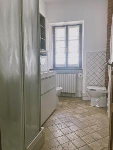 baño con ducha y aseo y ventana en Casa Lobe - Charming apartment in village centre, en La Morra