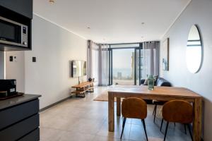 a kitchen and living room with a wooden table and chairs at Luxury Bellagio 302 with Sea Views and Inverter in Durban