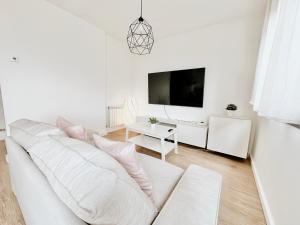 sala de estar blanca con sofá blanco y TV en Ático con Vistas al Mar a un Paso del Centro en Blanes