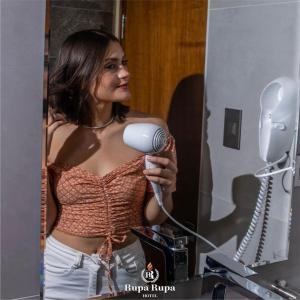 una mujer sosteniendo un secador de pelo delante de un espejo en Hotel Rupa Rupa, en Tingo María