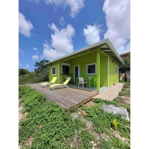 a small green house with a wooden deck at Les bungalows de Pipo 1 in Anse-Bertrand