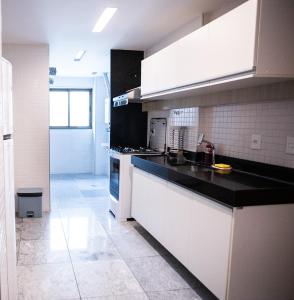 cocina con armarios blancos y encimera negra en Nobile Residences Maria Frazão en Recife