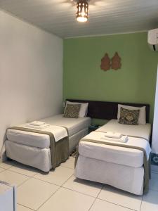 2 camas en una habitación con paredes verdes en Pousada Recôncavo en São Félix
