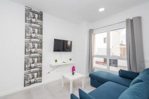 uma sala de estar com um sofá azul e uma televisão em Lightbooking 7 Palmas em Las Palmas de Gran Canaria