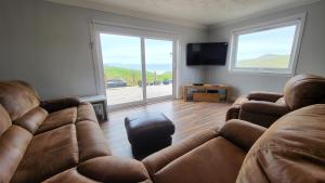 a living room with two couches and a television at Beachview in Oldshoremore