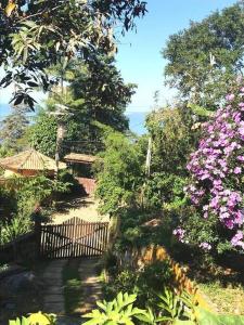 un jardín con flores rosas y una valla en Altar da praia Vermelha 180° de vista para o mar en Ubatuba