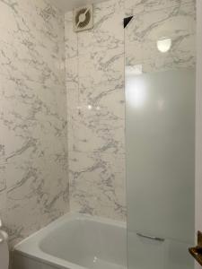 uma casa de banho com um chuveiro e uma banheira branca em West Kensington em Londres