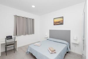 um quarto com uma cama e uma mesa com uma cadeira em Lightbooking 7 Palmas em Las Palmas de Gran Canaria