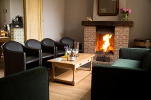 a room with chairs and a fireplace and a table at Holiday Home Slaghekhoeve in Nieuwkapelle