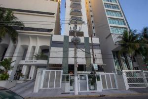 a building with white doors in front of tall buildings at Condomínio com aptos e lazer completo na Riviera in Riviera de São Lourenço