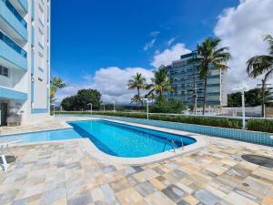 a swimming pool in front of a building with palm trees at Condomínio com aptos e lazer completo na Riviera in Riviera de São Lourenço