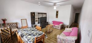 a living room with a table and chairs and a tv at Casa em Caraguatatuba com piscina e churrasqueira in Caraguatatuba