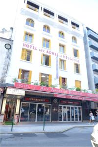 a large white building with a red sign on it at Hôtel Aux Armes de Belgique in Lourdes