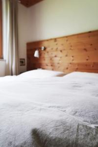 a bedroom with a white bed with a wooden headboard at Schöne Wohnung, zentral, mit Panorama-Aussicht in Grossarl