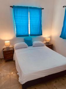 a bedroom with a large white bed with blue curtains at Caribbean Domicile in Las Terrenas