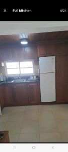 a kitchen with a white refrigerator and wooden cabinets at Juan Dolio Guababerry Resort in Juan Dolio
