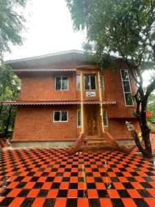 a house with a checkered floor in front of it at MTDC Vishwas Homestay, Kotawde, Ratnagiri in Ratnagiri