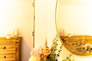 a vase of flowers sitting next to a mirror at Chapel Street Cottage in Coton in the Elms