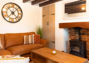uma sala de estar com um sofá e um relógio na parede em Chapel Street Cottage em Coton in the Elms