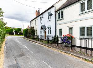uma rua vazia com casas brancas e uma cerca em Chapel Street Cottage em Coton in the Elms